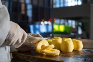 a imagem contém uma pessoa em uma indústria, cortando alimentos