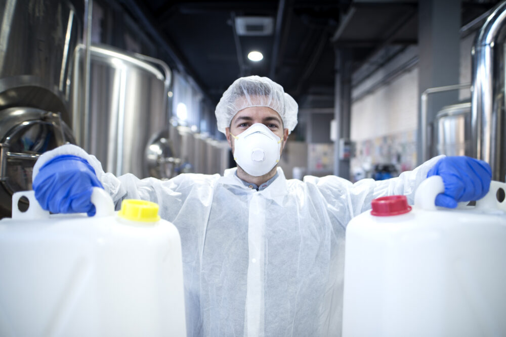 trabalhador industrial segurando duas latas de produto biodegradável